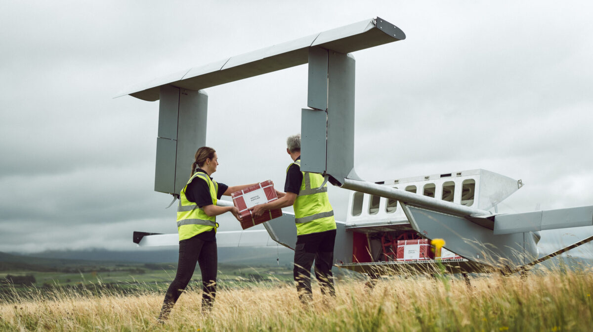 Delivery workers placing package inside Windracers Ultra drone aircraft